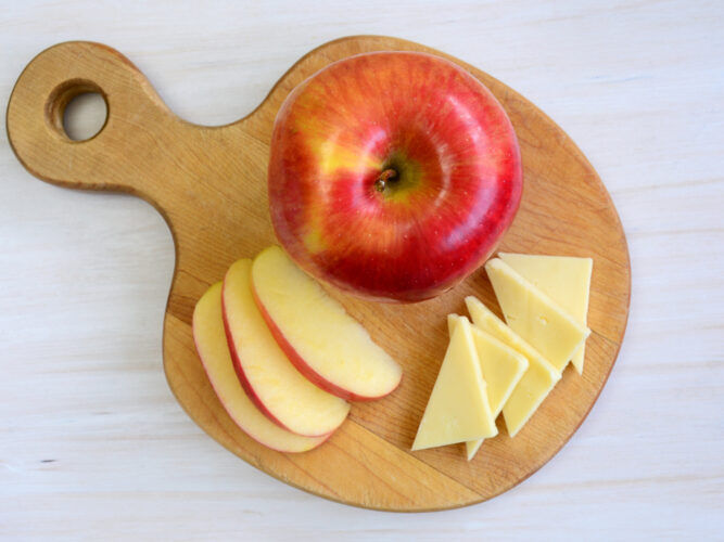 apple and slices of cheese on a cutting board