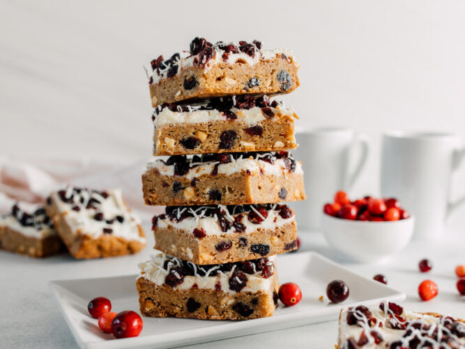 homemade cranberry bliss bars stacked on top of each other on a plate