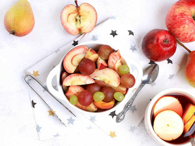 fall fruit salad in a bowl next to hot apple cider
