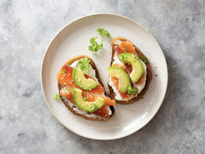 salmon avocado toast on a plate with herbs
