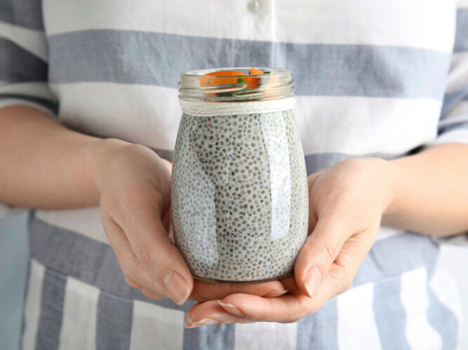 woman holding a jar of chia seed pudding with fruit