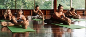 A group of people attending a yoga class in a tropical environment of a yoga meditation retreat